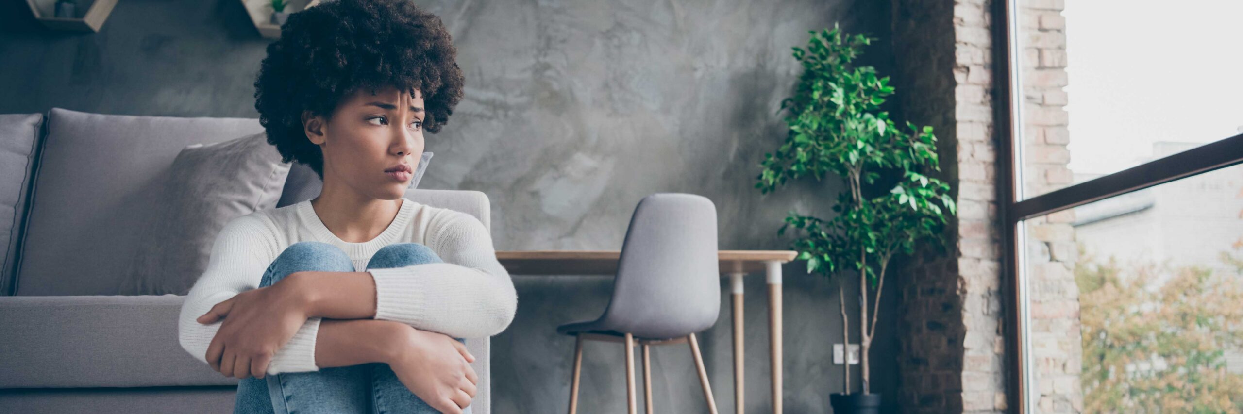 Woman with a worried look sitting on floor | Pelvic Inflammatory Disease and Infertility | Ember Fertility Center | Orange County, CA