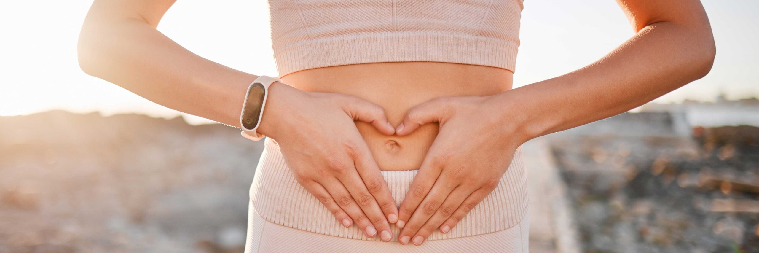Women with blocked fallopian tubes hold her hands in a heart shape over her abdomen | Ember Fertility Center | Laguna Hills & Orange County, CA